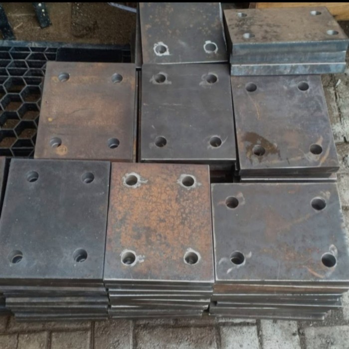 Stacked Heavy Iron Base Plates Ready for Thickness Check A stack of raw rectangular iron base plates with pre-drilled holes kept in a workshop for checking thickness and dimensions.